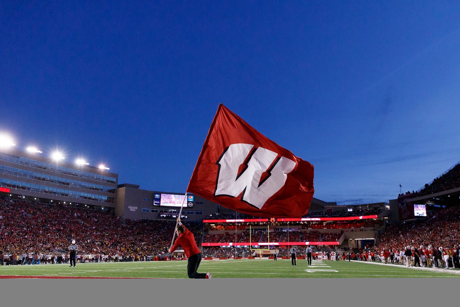 The Wisconsin flag being ran across the end zone at Camp Randall Stadium.